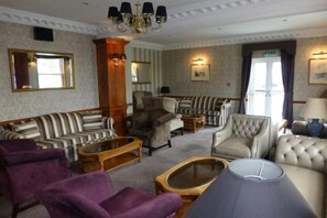 Eine Hotel-Lounge mit gestreiften Sofas, Sesseln und einem Ottomanen sowie einem Couchtisch.