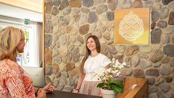 Un mostrador de recepción con un fondo de pared de piedra, una planta en maceta y un logotipo enmarcado en la pared.