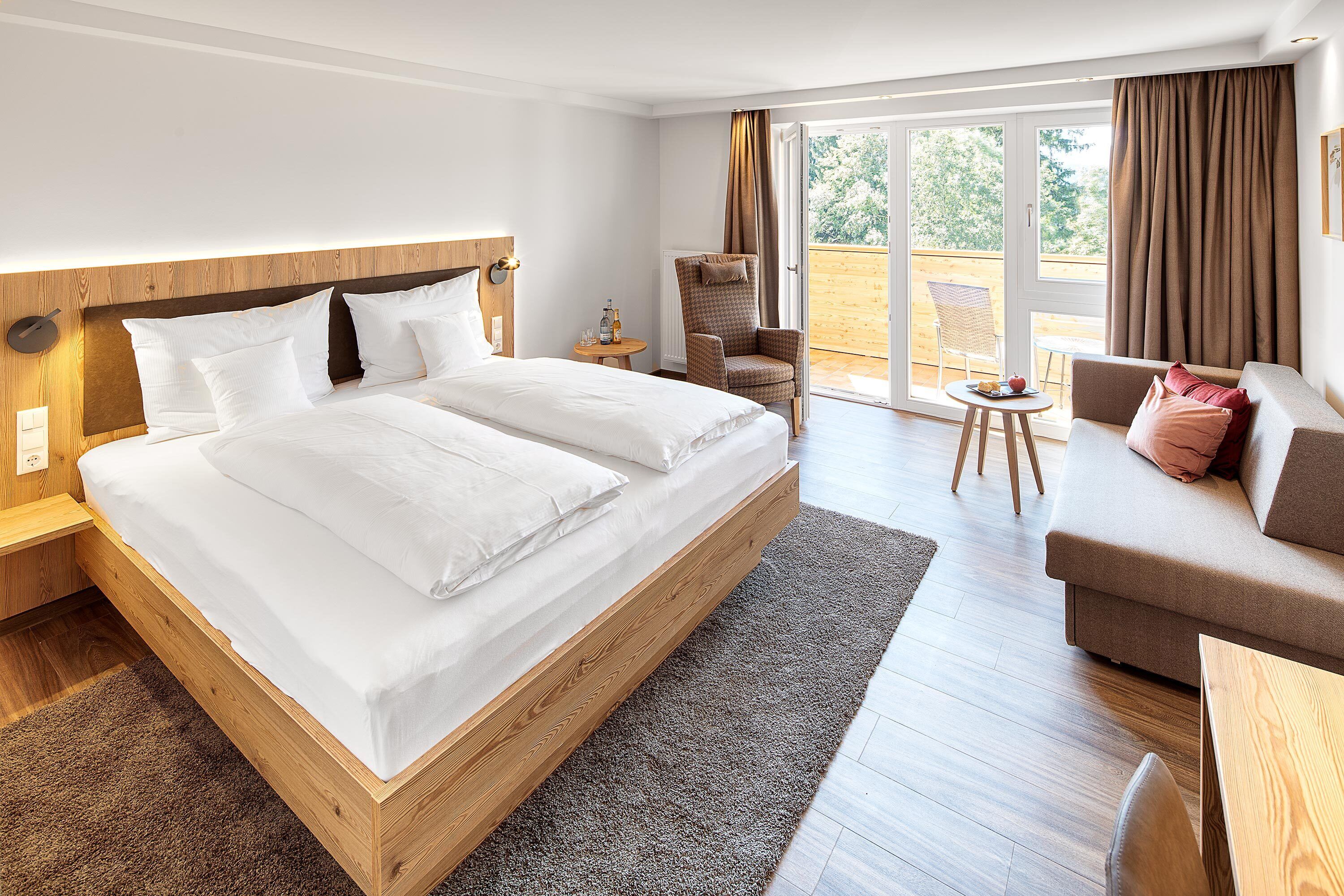 Una habitación de hotel moderna con una cama grande, un sofá, una silla y una mesita.