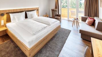 Una habitación de hotel moderna con una cama grande, un sofá, una silla y una mesita.