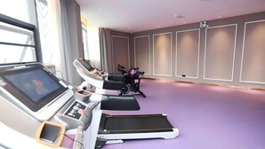 Un gimnasio con equipo de ejercicio, un ventanal grande y piso color púrpura.