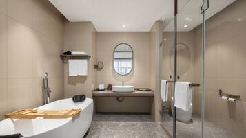 A modern bathroom with a freestanding bathtub, a vanity with a mirror, and a glass-enclosed shower.
