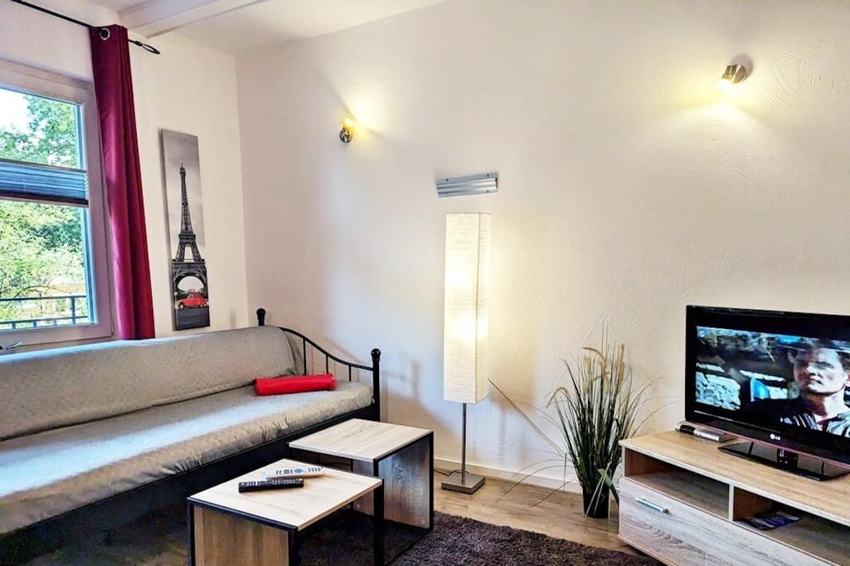 A modern living room with a sofa, a coffee table, a TV, and a lamp.