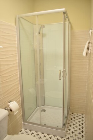 A glass-enclosed shower stall with a white floor and patterned tiles. - Casa Rural Herrera (Villacarrillo)