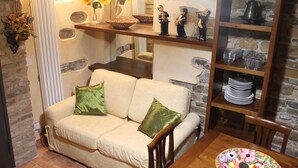 A cozy living room with a beige sofa, green cushions, a wooden coffee table, and a decorative plate of pastries.