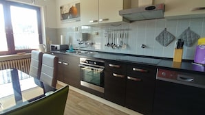 A modern kitchen with stainless steel appliances, a built-in oven, and a window providing natural light. - Apartmenthaus Abendsonne (Koblenz)