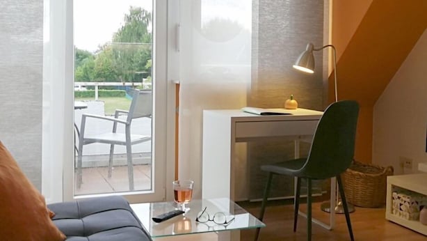 A modern living room with a glass coffee table, a sofa, a desk with a chair, and a lamp. - Apartmenthaus Abendsonne (Koblenz)