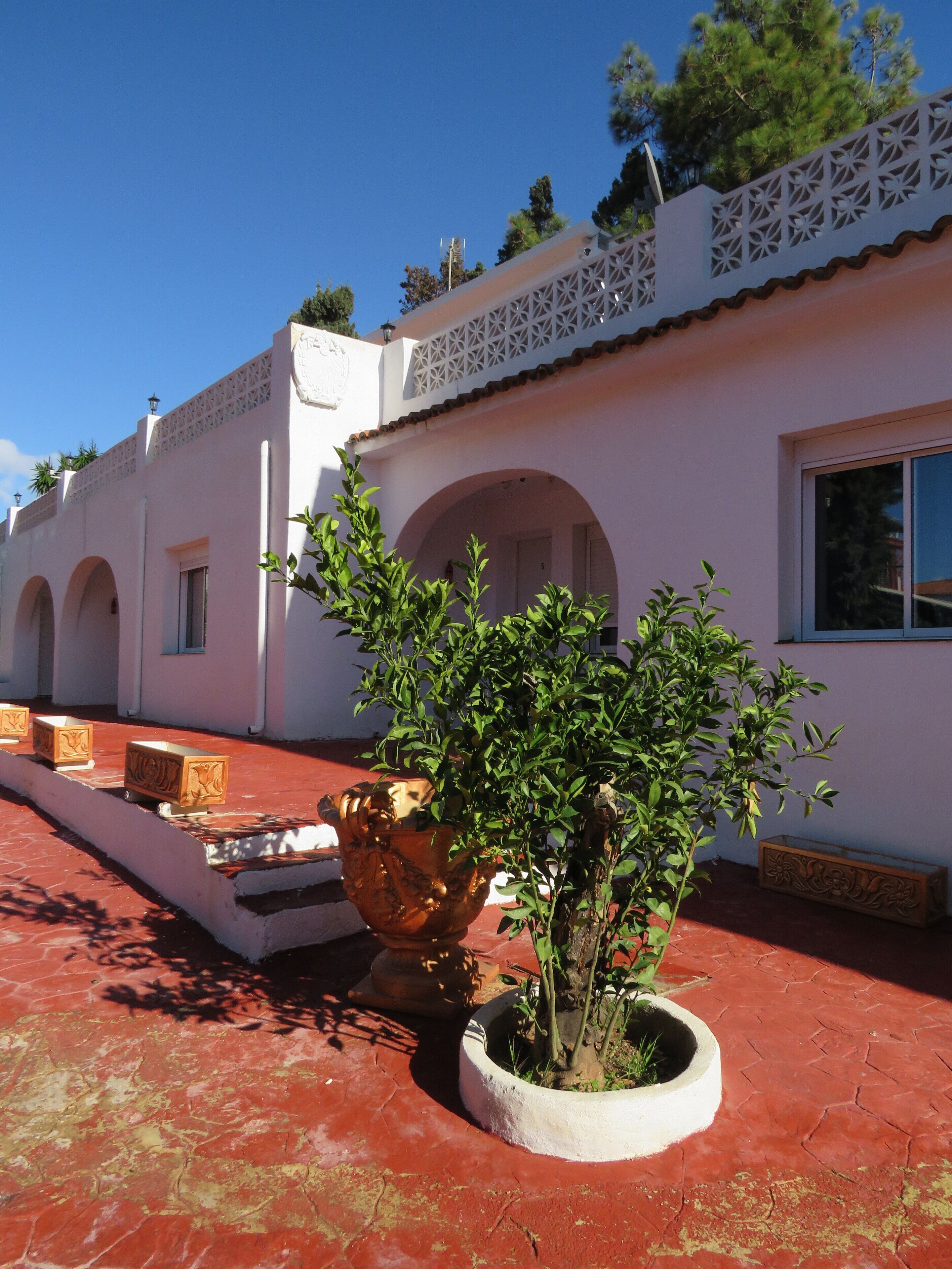 A building with white walls, arches, and a red tiled floor.