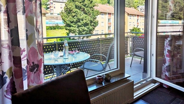 A room with a large window, a table with chairs, and a radiator. - Ferienwohnung Koblenz City (Koblenz)