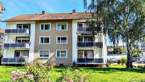 A multi-story residential building with balconies, a well-maintained lawn, and a large tree in the foreground. - Ferienwohnung Koblenz City (Koblenz)