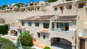 A Mediterranean-style villa with multiple balconies, a courtyard, and a view of the surrounding hillside. - Miramar by Interhome (Moraira)