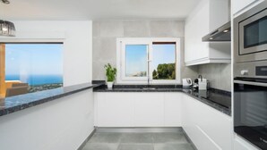 A modern kitchen with a view of the sea, a large window, and a built-in oven. - Miramar by Interhome (Moraira)