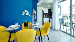 Uma sala de jantar moderna com uma parede azul como destaque, cadeiras amarelas e uma mesa de vidro.