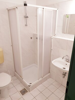 A bathroom with a glass-enclosed shower, a white sink, and a toilet. - Summer Residence - Hostel (Ljubljana)