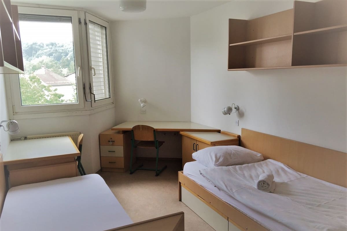 A bedroom with a single bed, a desk, and a chair.