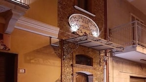 Ein Gebäude mit einer Stein-Fassade, einer Holztür und einem Balkon mit Metallgitter.