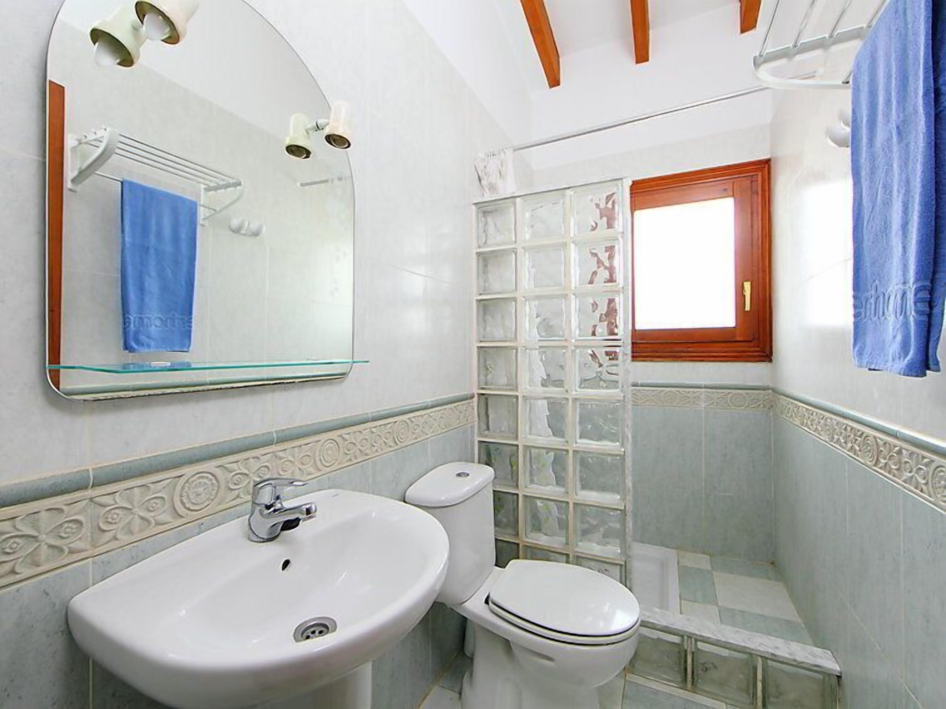 A bathroom with a white sink, toilet, and a glass shower enclosure.