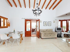 A spacious living area with a dining table, chairs, a sofa, and a TV.