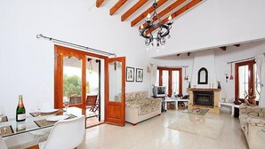 A spacious living room with a glass dining table, a sofa, a fireplace, and a chandelier. - Esperanza by Interhome (Pego)