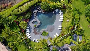 An aerial view of a landscaped pool area with multiple seating areas and a central water feature. - 🏖️Family-Friendly | Pools, Beach Gear, Golf & Walk to A-Bay Adventures (Waikoloa)