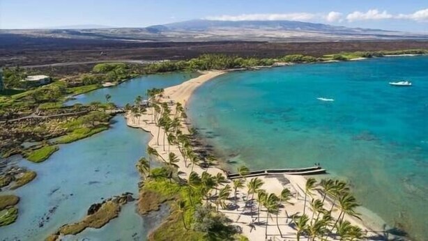 An aerial view of a coastal area with a beach, clear blue waters, and a boat. - 🏖️Family-Friendly | Pools, Beach Gear, Golf & Walk to A-Bay Adventures (Waikoloa)