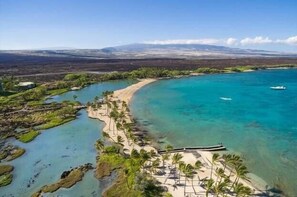 A coastal area with clear turquoise waters, a sandy beach, and a boat docked near the shore. - 🏖️Family-Friendly | Pools, Beach Gear, Golf & Walk to A-Bay Adventures (Waikoloa)