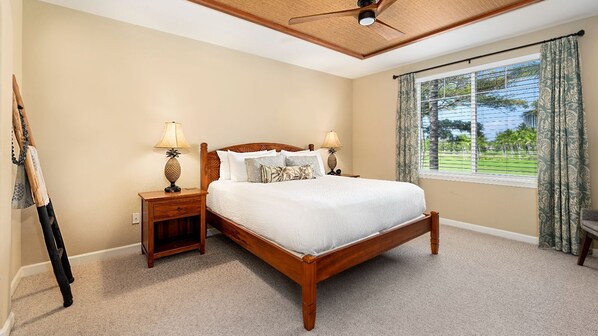 A bedroom with a wooden bed, two nightstands with lamps, a ceiling fan, and a large window with curtains. - 🏖️Family-Friendly | Pools, Beach Gear, Golf & Walk to A-Bay Adventures (Waikoloa)