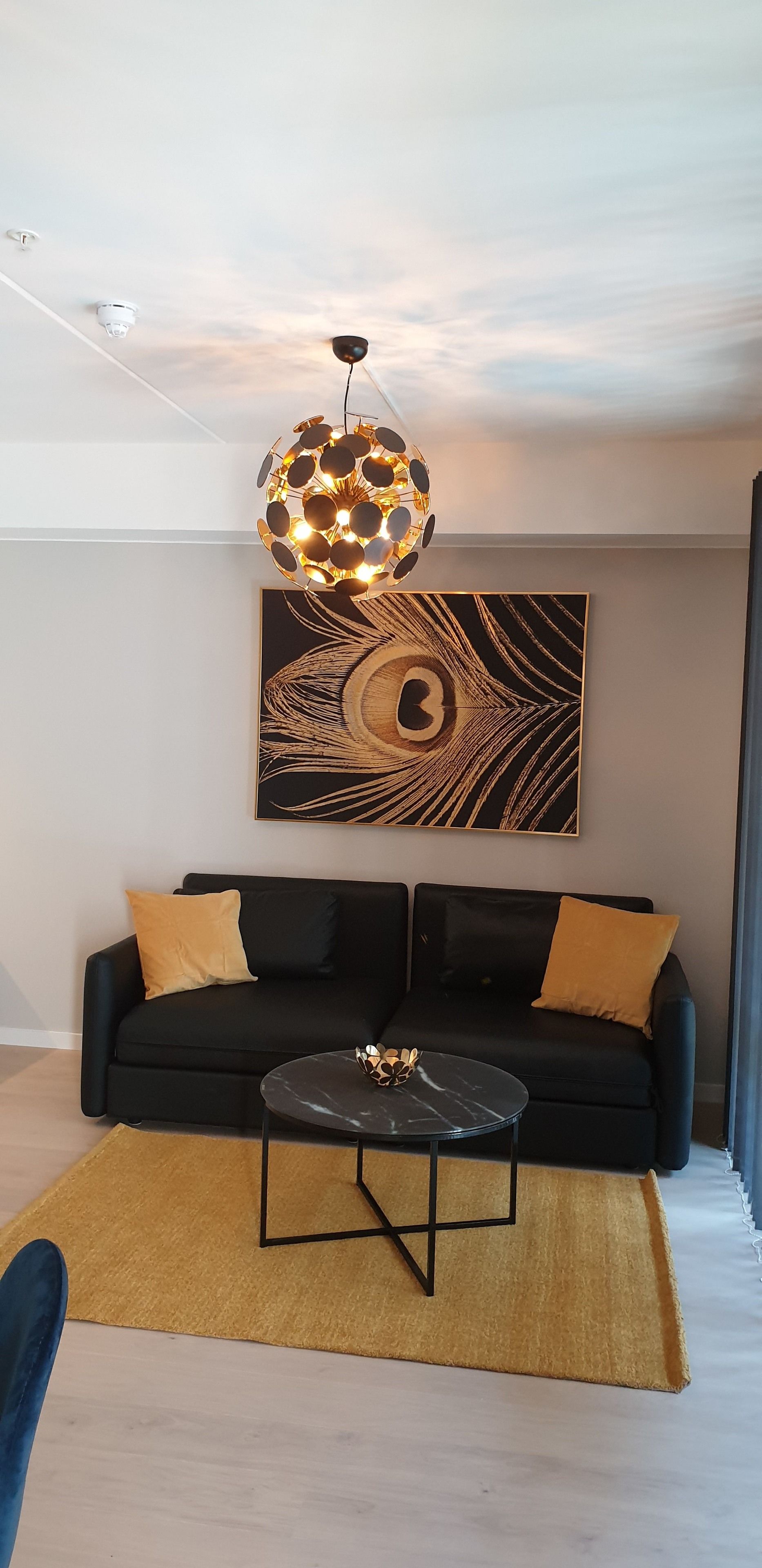 A modern living room with a black sofa, a round coffee table, and a unique spherical light fixture.