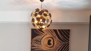 Un soggiorno moderno con un divano nero, un tavolino rotondo e un lampadario sferico originale.