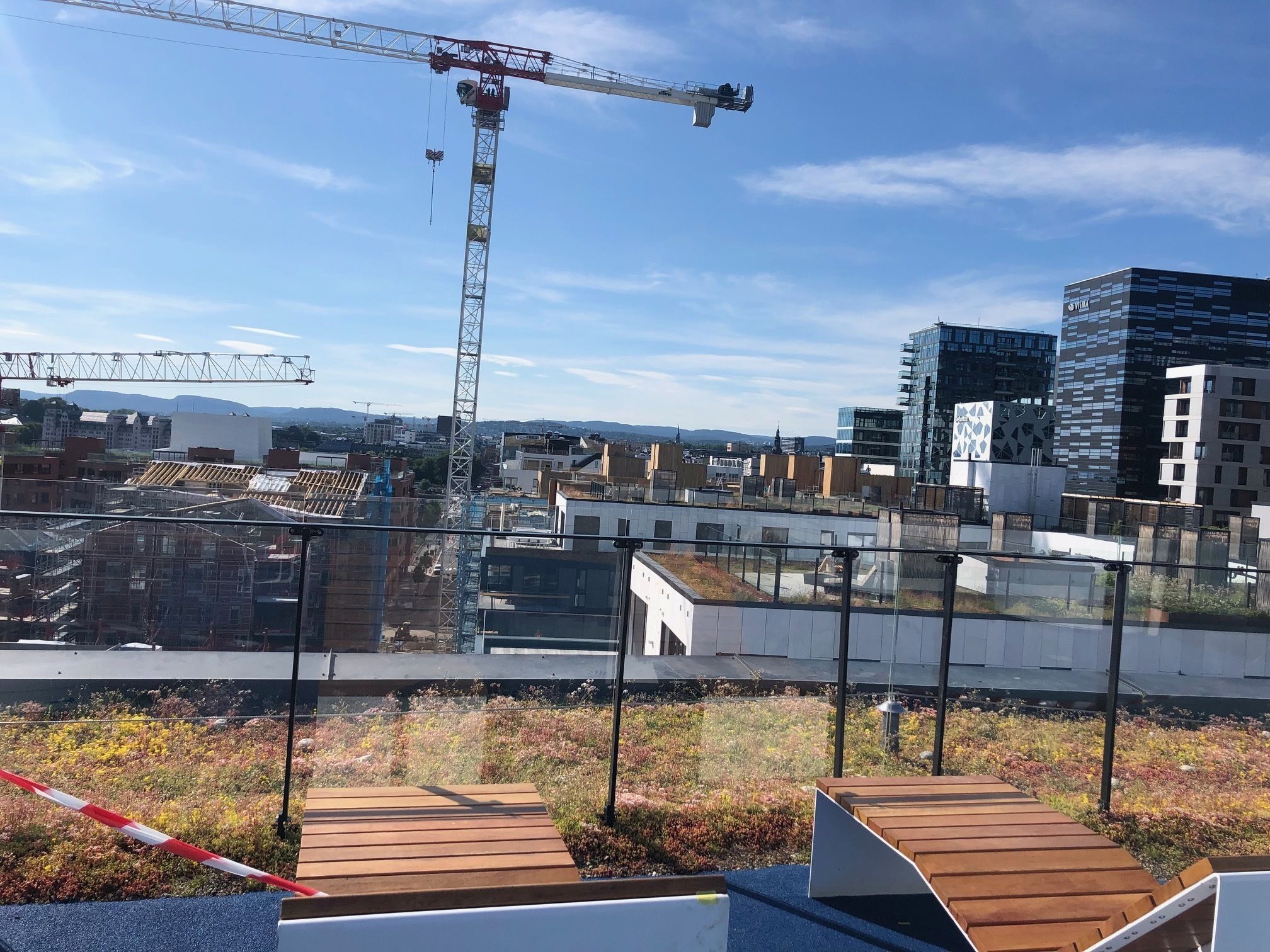 En tagterrasse med udsigt over bybilledet, inklusive moderne bygninger og en byggekran.