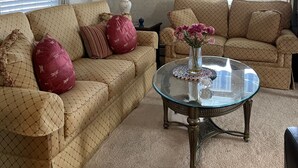 A living room with two beige patterned sofas, a glass coffee table, and a lamp. - OCNJ Gold Coast beach home, Pet friendly, 9 houses from the beach and boards!  (Ocean City)