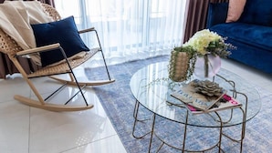 A modern living room with a glass coffee table, a rocking chair, and a blue sofa. - Magical 3BR/Parking with amazing view, city center (Jerusalem)