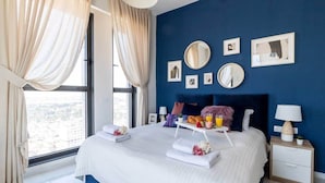A modern hotel room with a large bed, a nightstand, a bedside table, and a view of the city through the window. - Magical 3BR/Parking with amazing view, city center (Jerusalem)