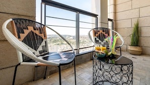 A balcony with two chairs and a table, a potted plant, and a view of the city. - Magical 3BR/Parking with amazing view, city center (Jerusalem)