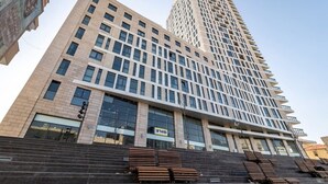 A modern high-rise building with a prominent glass facade and a series of balconies. - Magical 3BR/Parking with amazing view, city center (Jerusalem)