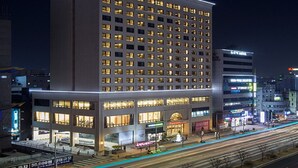 A multi-story building with "RAMADA" signage, featuring a ground-level retail space and multiple illuminated windows.