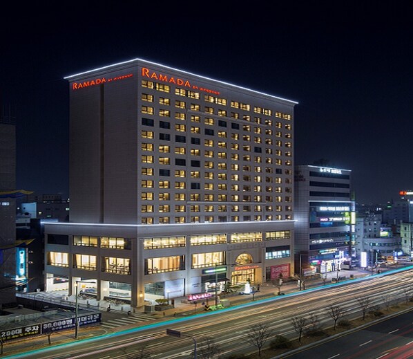 A multi-story building with "RAMADA" signage, featuring a ground-level retail space and multiple illuminated windows. - Ramada by Wyndham Daejeon (Daejeon)