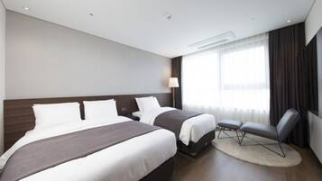 A modern hotel room with two beds, a desk, a chair, and a large window with curtains.