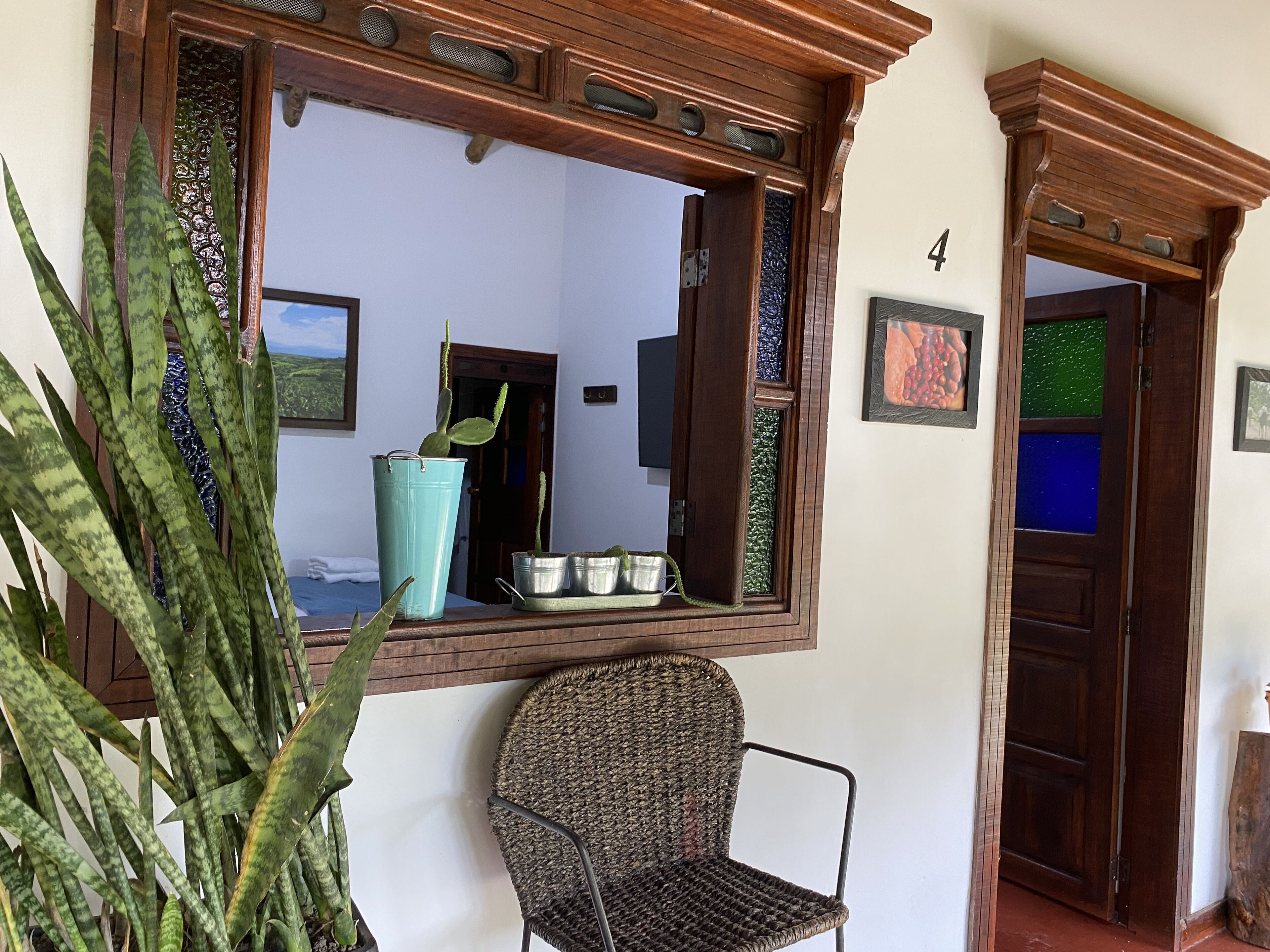 Une pièce avec un grand miroir, une chaise, une plante en pot et une porte portant un numéro.
