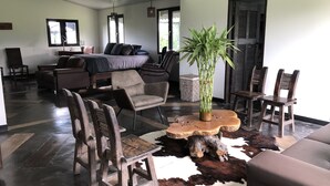 A spacious living area with a sofa, chairs, a coffee table, and a potted plant. - Finca Hotel Brasilia (La Tebaida)