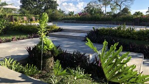 A garden pathway with various plants and a clear blue sky. - Finca Hotel Brasilia (La Tebaida)