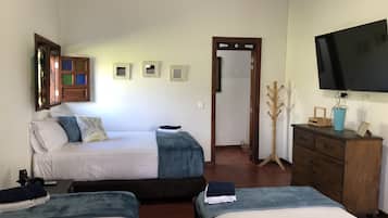 Quarto com duas camas, penteadeira de madeira, televisão e espelho.