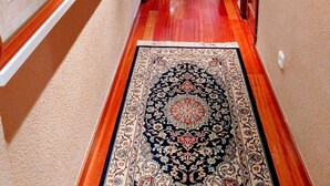 Un couloir aux murs ornés de tableaux encadrés, avec un tapis à motifs et un plancher en bois.