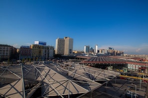 A cityscape with a large, open plaza featuring a modern, geometric roof structure. - Bayard101 (Naples)