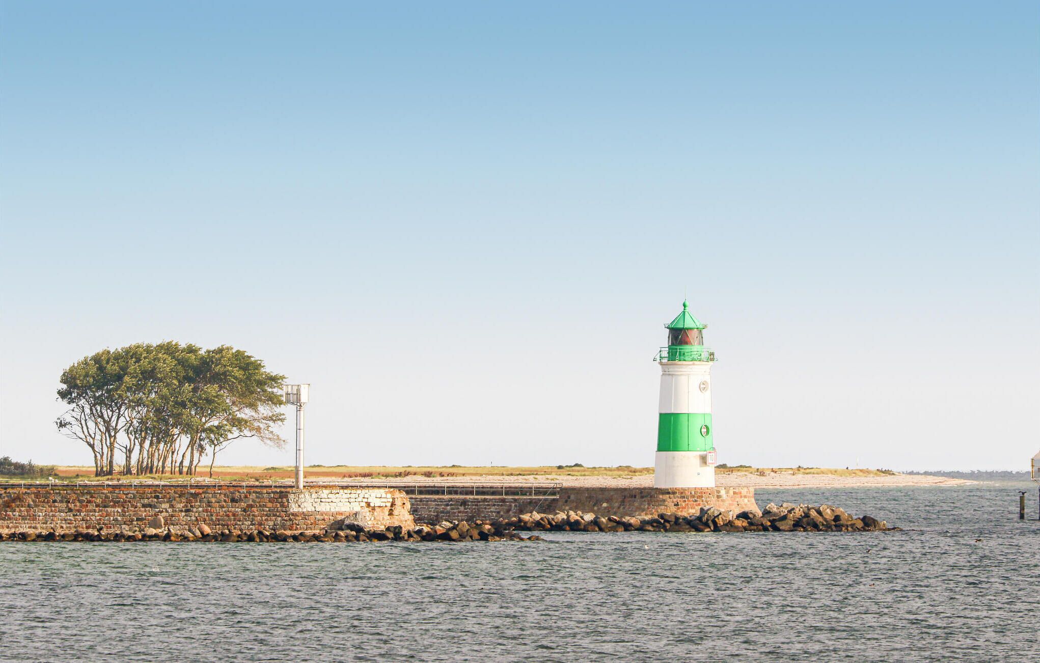 A lighthouse on a rocky outcrop with a clear sky.