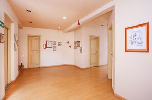 A hallway with wooden floors, beige walls, and framed pictures on the walls. - Grand Residences Pousadas (Campos do Jordão)