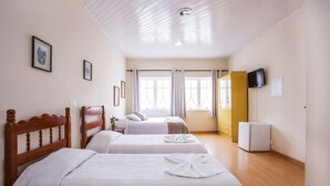 Une chambre d’hôtel avec deux lits, une télévision, un réfrigérateur et une fenêtre avec des rideaux.