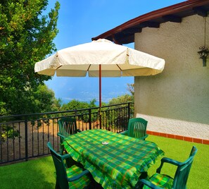 Une terrasse avec une table et des chaises, un parasol et une vue sur la mer.