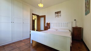 Ein Schlafzimmer mit Bett, Nachttisch, Schrank und einer Tür zu einem anderen Raum.