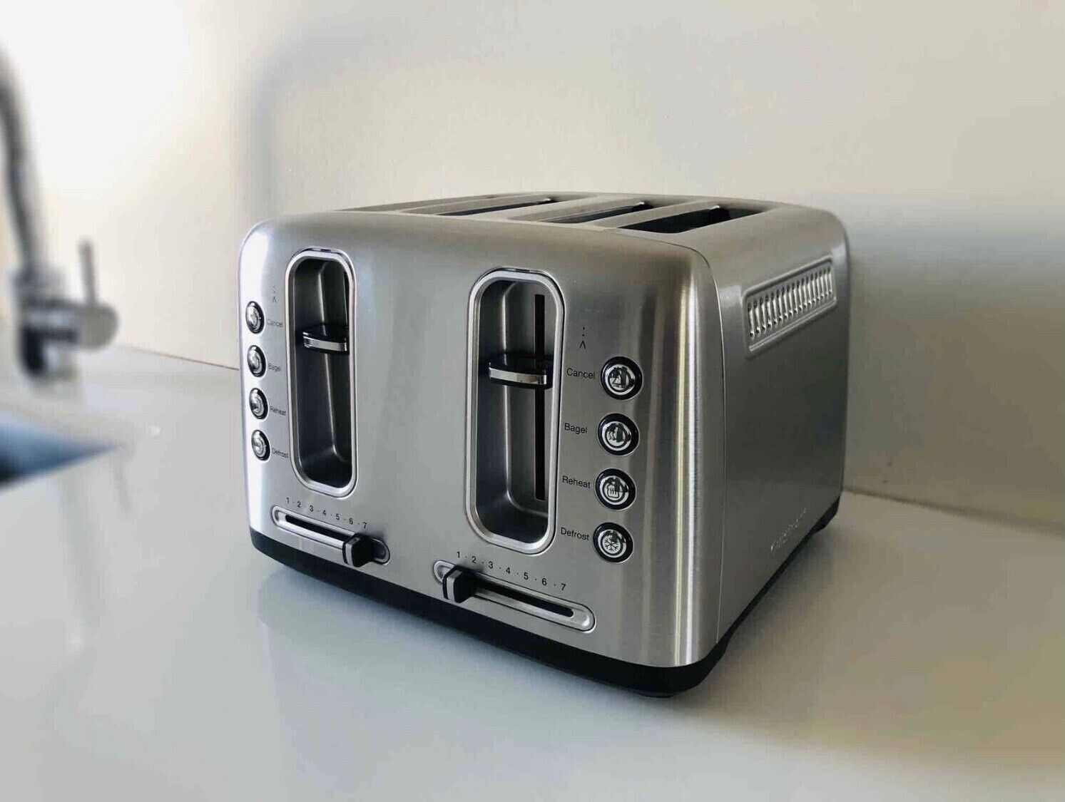 A modern kitchen with a stainless steel toaster on a white countertop.